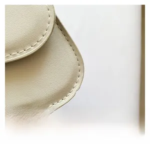 Detailed macro view of cream-white lychee textured faux leather with neat edge stitching