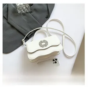 Detail of white wave-edge flap handbag featuring a centered rhinestone buckle and top handle