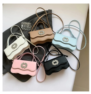 Flat lay of small crossbody bags with wave flap edges and rhinestone buckle details