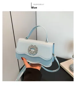 Detail shot of light blue crossbody bag with sparkling rhinestone ring buckle and wave flap