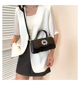 Detail view of stylish black bag featuring wave-edge flap and sparkling crystal buckle