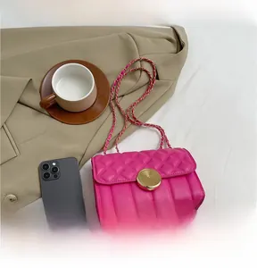 Close-up of rose pink quilted chain bag with gold textured buckle on beige blazer