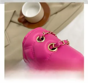 Detail of rose red quilted crossbody bag with gold chain strap and metal hardware