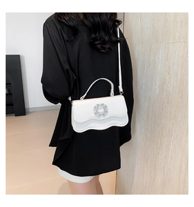Detail view of the white handbag showing the wave edge and large rhinestone buckle