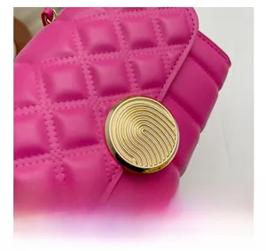 Macro detail of golden magnetic buckle on rose red quilted crossbody bag with metal texture