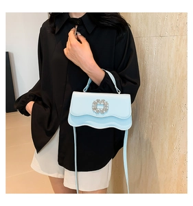 Detail of light blue wave-edge handbag with sparkling floral rhinestone buckle detail