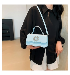 Light blue crossbody bag featuring a wavy flap design and a luxury rhinestone buckle