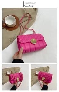 Macro shot of rose red quilted chain bag with gold rotary lock and leather strap
