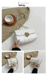 Detail of white quilted mini chain bag with gold rotary clasp and leather strap