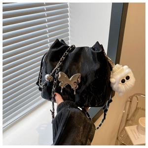 Detail of black drawstring bucket bag with silver butterfly buckle and chain strap