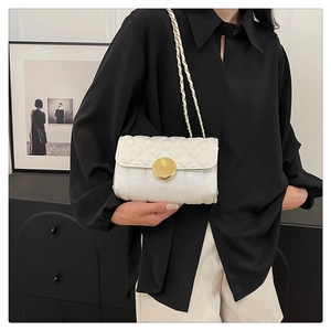 Detail of white quilted crossbody bag featuring a designer gold spiral twist lock buckle