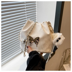 Détail d'un sac seau blanc avec texture plissée et décoration papillon argentée