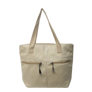 Large beige canvas tote bag with front zipper pockets shown against a white background