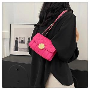 Rear view of a model wearing a hot pink quilted crossbody bag with golden chain strap
