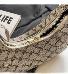 Close-up of smooth gold-tone zipper and clover pattern texture on beige shoulder bag