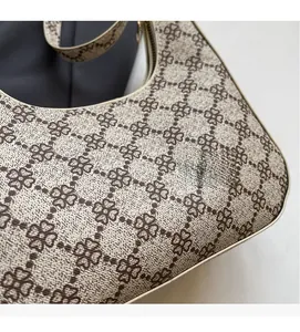 Detailed close-up of clover lattice pattern on a beige commute crescent shoulder bag