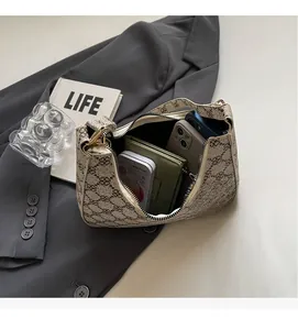 Spacious interior of beige crescent shoulder bag with monogram print holding daily essentials