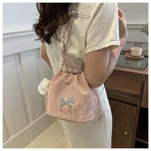 Detail of pink drawstring bucket bag with metal butterfly buckle and chain strap