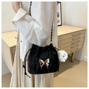Détail du sac seau noir avec papillon en métal liquide et porte-clé chat en peluche