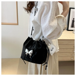 Détail du sac seau noir à cordon avec papillon argenté et pompon blanc en intérieur doux