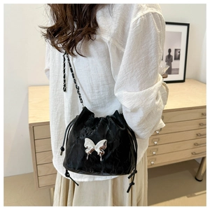 Detail of black drawstring bucket bag featuring a silver butterfly metallic ornament