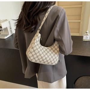 Detail of a crescent shoulder bag with brown clover print on a beige textured material