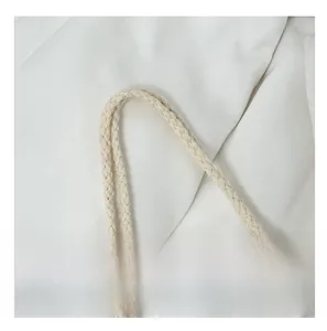 Detail of thickened cream cotton rope handles and white canvas fabric on a beach tote