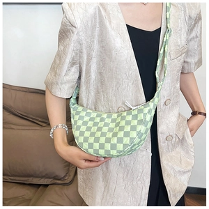 Borsa a mezzaluna trapuntata a scacchi verde con tracolla abbinata su un blazer beige