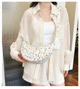 Detailed view of floral crossbody bag with white lace bow and wide shoulder strap
