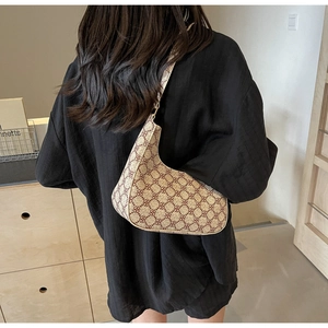 Close-up of retro brown monogram crescent shoulder bag worn on a female model's shoulder