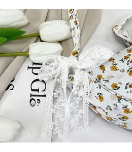 Detail of floral canvas bag featuring a large white lace bow and yellow flower pattern