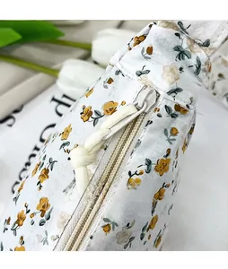 Detail view of floral fabric shoulder bag with smooth metal zipper pull and woven knot