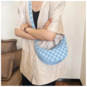 Dettaglio della borsa hobo a scacchi azzurra indossata come borsa a tracolla alla moda