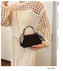 Detail of black box bag with lattice texture and scarf wrapped around the top handle