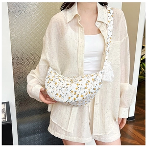 Close-up of crescent-shaped floral crossbody bag with white lace trim and wide strap