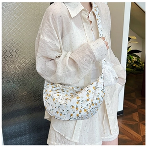 Detail of floral canvas dumpling bag with white lace bow and yellow flower pattern