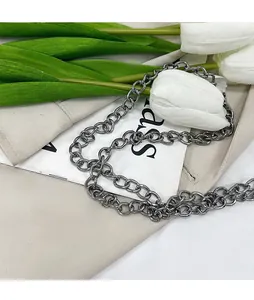Close-up of gun-gray metal chain strap on beige blazer with white tulip decoration