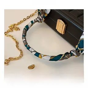 Close-up of black plaid handbag featuring silk scarf wrapped handle and gold hardware