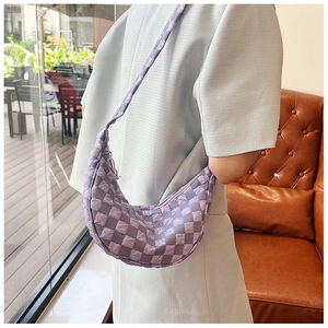 Dettaglio della borsa a mezzaluna trapuntata a scacchi viola indossata da una modella