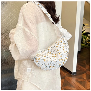 Close-up of floral canvas dumpling bag with white lace bow decoration and adjustable strap