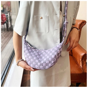 Dettaglio di una borsa a tracolla trapuntata a scacchi viola e grigia indossata da una modella