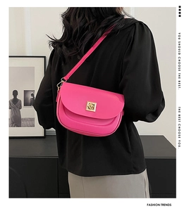Détail du sac en cuir rose vif avec boucle géométrique dorée porté par un mannequin