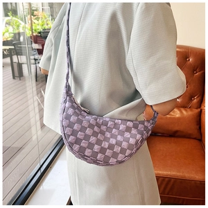 Dettaglio della borsa a mezzaluna trapuntata viola con trama a bolle portata come sottospalla