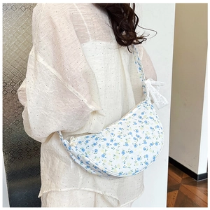 Detailed close-up of a crescent floral canvas bag with white lace bow and blue flower print