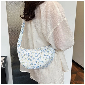 Detail of floral crescent crossbody bag featuring blue and yellow prints on white faux leather