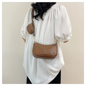 Détail d'un sac à bandoulière marron tressé avec petit porte-monnaie rond assorti