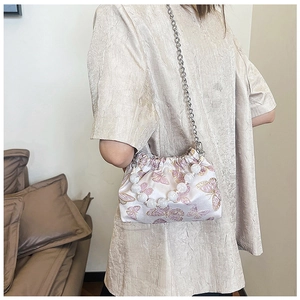 Detail of pink satin bucket bag with golden butterfly embroidery and pearl strap