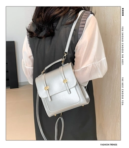 Detail of silver metallic mini backpack with dual gold buttons and versatile straps
