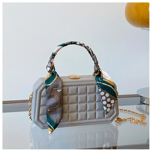 Detailed view of grey quilted box bag featuring a decorative silk scarf and gold hardware