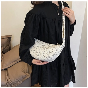 Detail shot of floral print crossbody bag with crescent shape and metal zipper closure